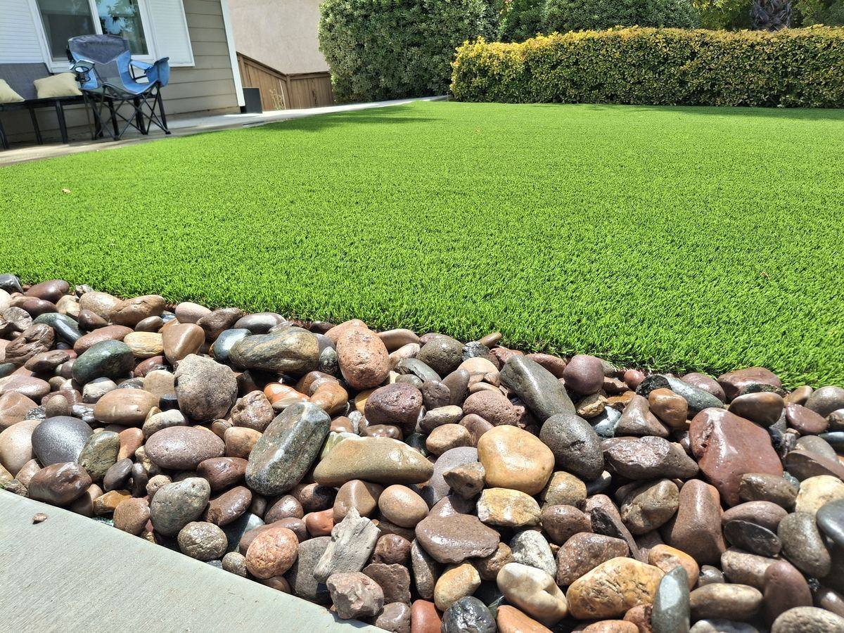 Eco 82 artificial grass: Front lawn with a river-rock border, installed by Synthetic Grass Techs in Moreno Valley