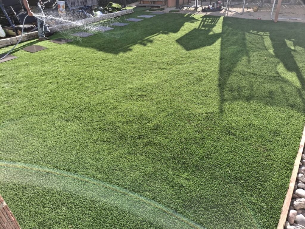 Rinsing a backyard artificial grass lawn with a sprinkler