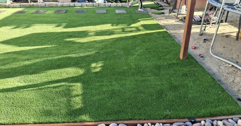 Backyard artificial grass play area with a trampoline and swing set
