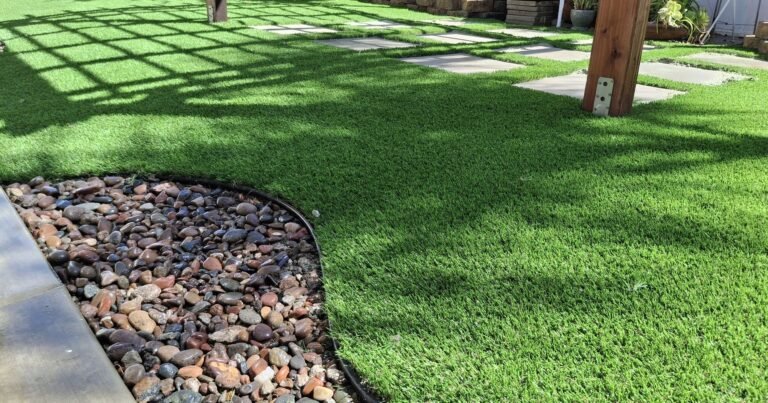 Backyard artificial grass with a curved river rock border and pergola