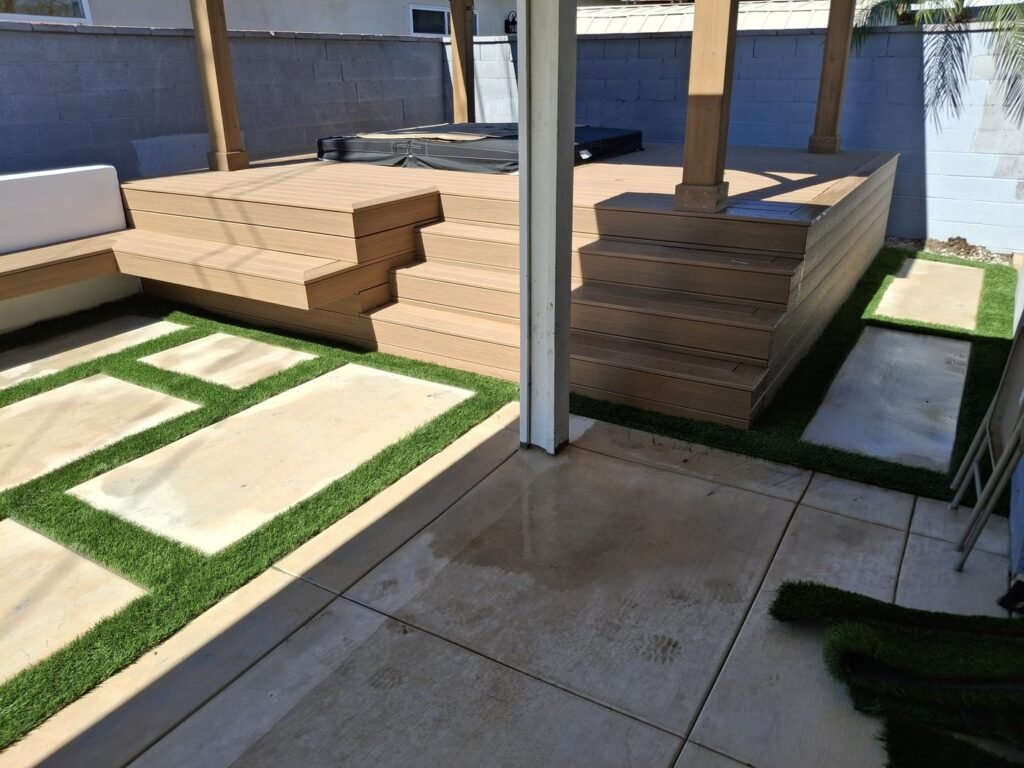 Concrete pads with artificial grass strips beside a deck