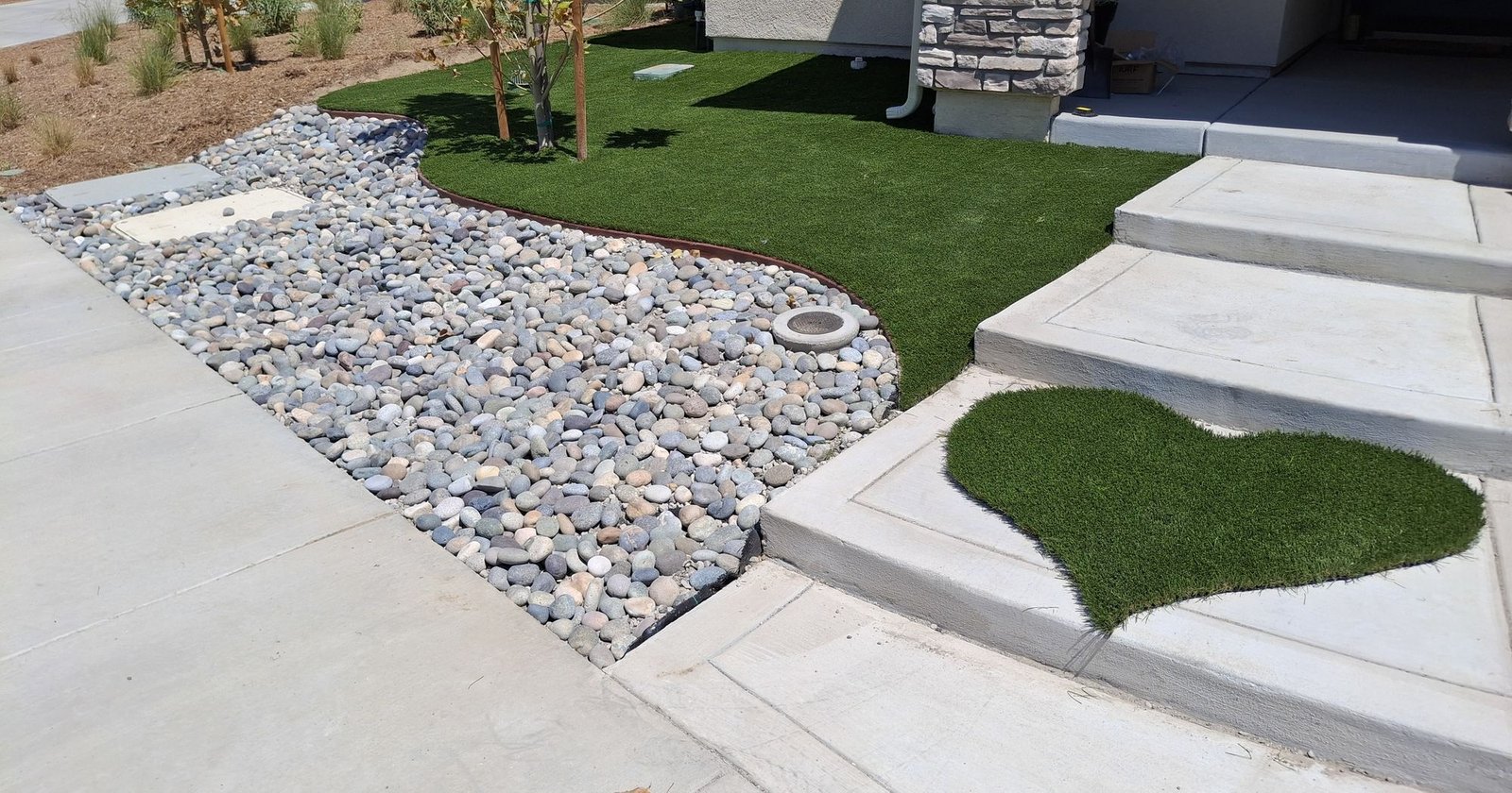Front yard artificial grass with a turf heart by the steps and a river rock bed