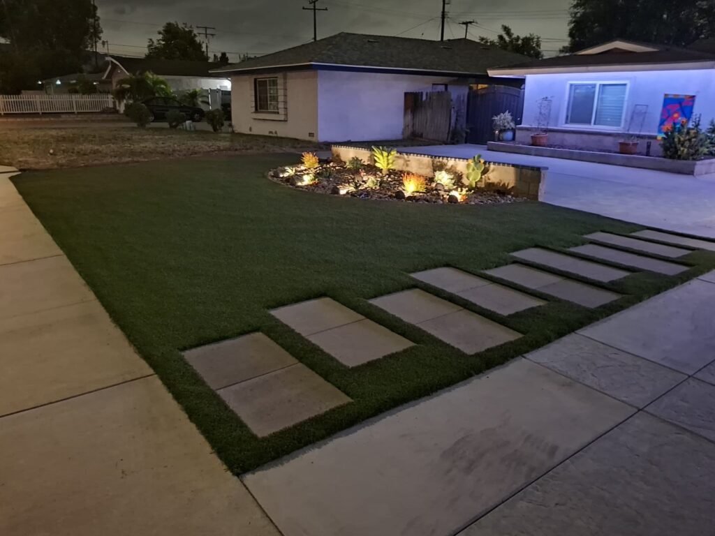 Front yard artificial grass and stepping pads with landscape lighting at night