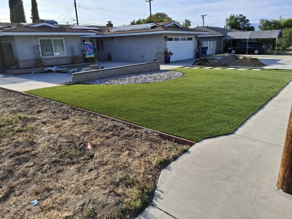 Front yard artificial grass with a raised planter and metal edging