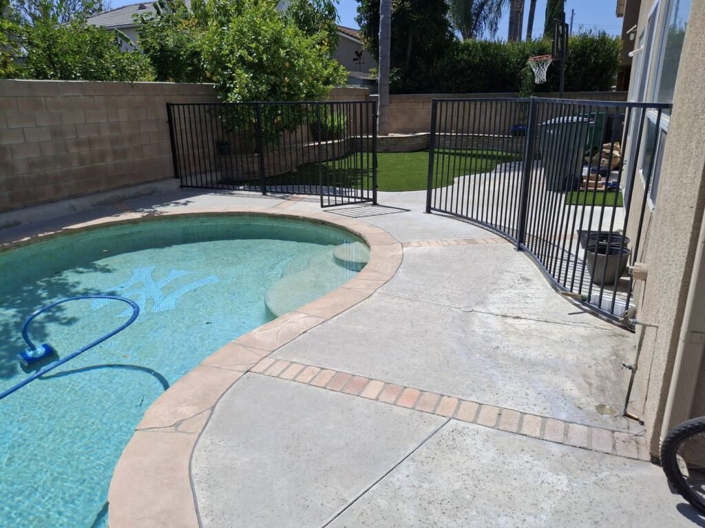 Backyard pool with artificial grass behind the pool fence