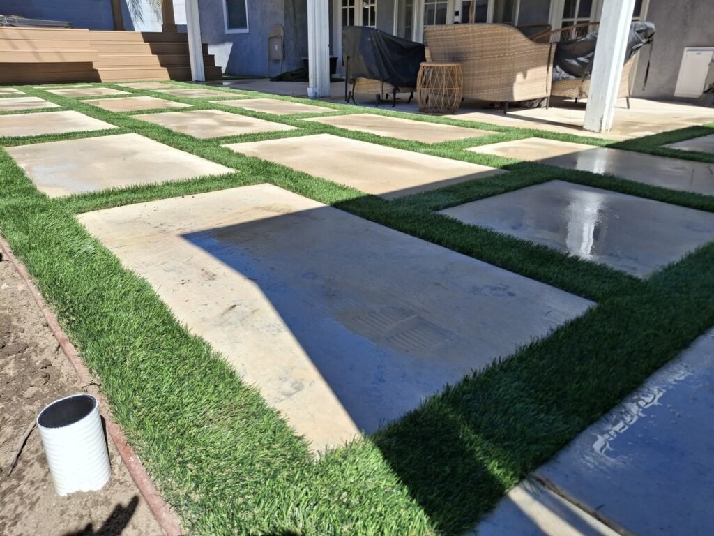Artificial grass strips between concrete pads in a backyard